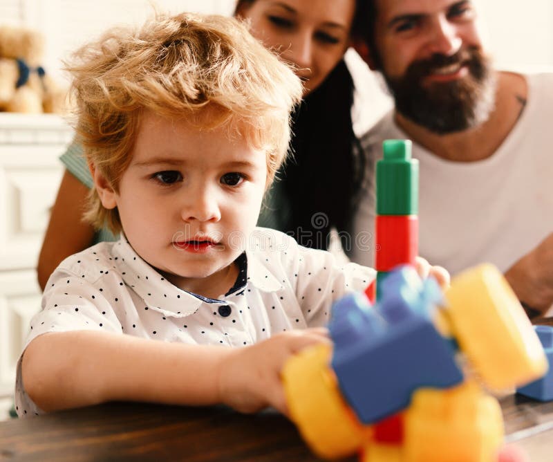 Parents Watch Kid Playing with Yellow and Blue Bricks pic