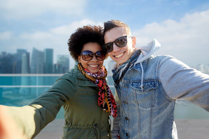 Pares adolescentes felizes que tomam o selfie em singapore imagens de stock Pares adolescentes felizes que tomam o selfie em singapore imagens de stock