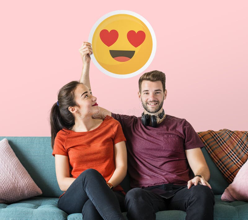 Pares alegres que sostienen un emoticon de los ojos del corazón foto de archivo libre de regalías Pares alegres que sostienen un emoticon de los ojos del corazón foto de archivo libre de regalías