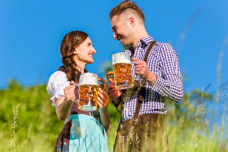 Pares alemanes en Tracht con la cerveza, pretzel imagen de archivo libre de regalías Pares alemanes en Tracht con la cerveza, pretzel imagen de archivo libre de regalías