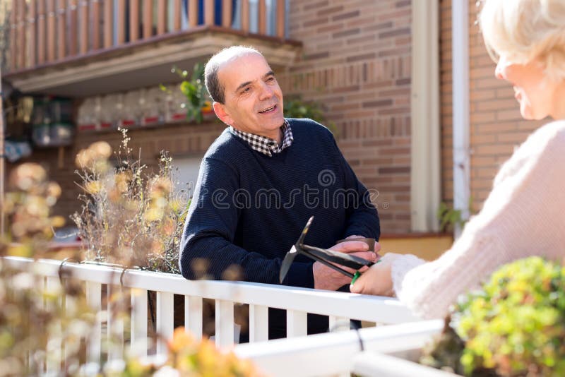 Pares aposentados que falam no pátio fotografia de stock Pares aposentados que falam no pátio fotografia de stock