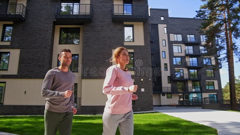 Pares ativos felizes que correm no parque próximo com casa