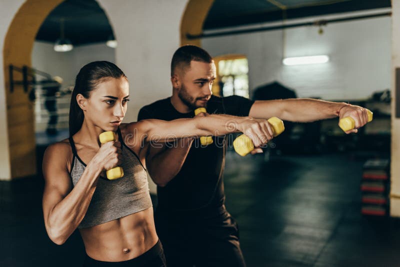 Pares atléticos que ejercitan con pesas de gimnasia imagen de archivo libre de regalías Pares atléticos que ejercitan con pesas de gimnasia imagen de archivo libre de regalías