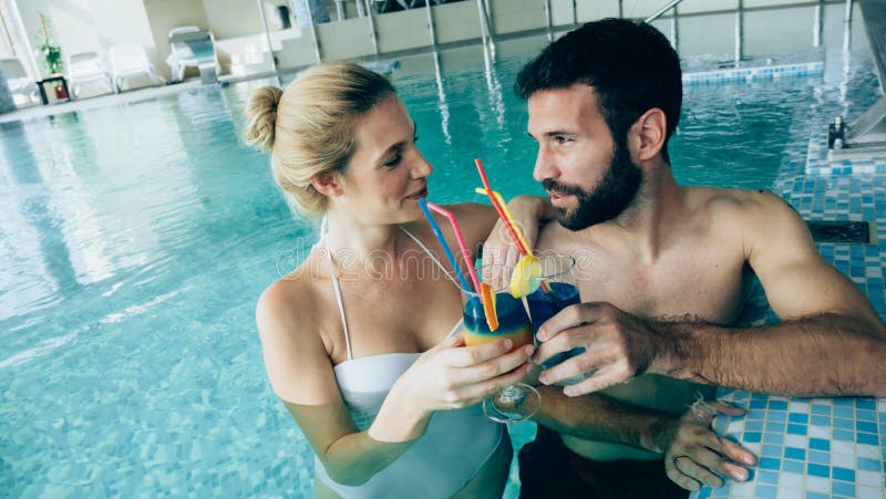 Pares atractivos felices que se relajan en piscina foto de archivo libre de regalías Pares atractivos felices que se relajan en piscina foto de archivo libre de regalías