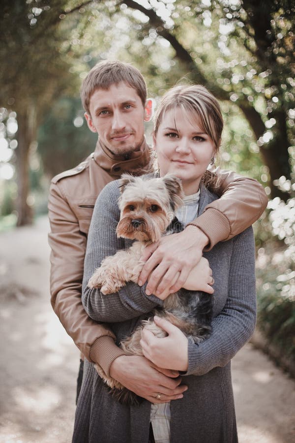 Pares atrativos novos que vão para uma caminhada com seu cão foto de stock Pares atrativos novos que vão para uma caminhada com seu cão foto de stock