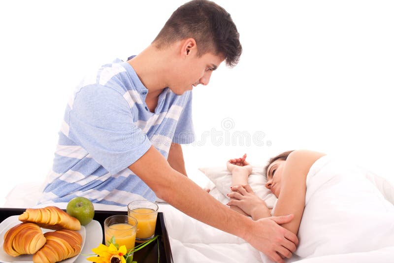 Pares bonitos que comem o pequeno almoço encontrar-se na cama imagem de stock Pares bonitos que comem o pequeno almoço encontrar-se na cama imagem de stock