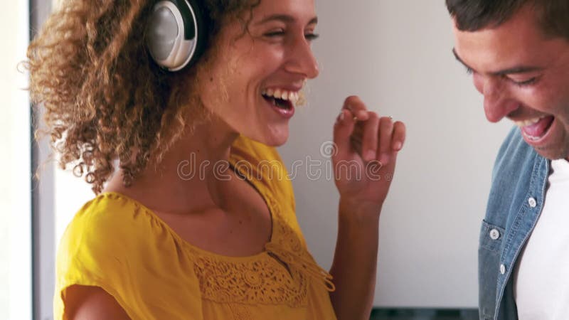 Pares bonitos que escutam a música com fones de ouvido e dança