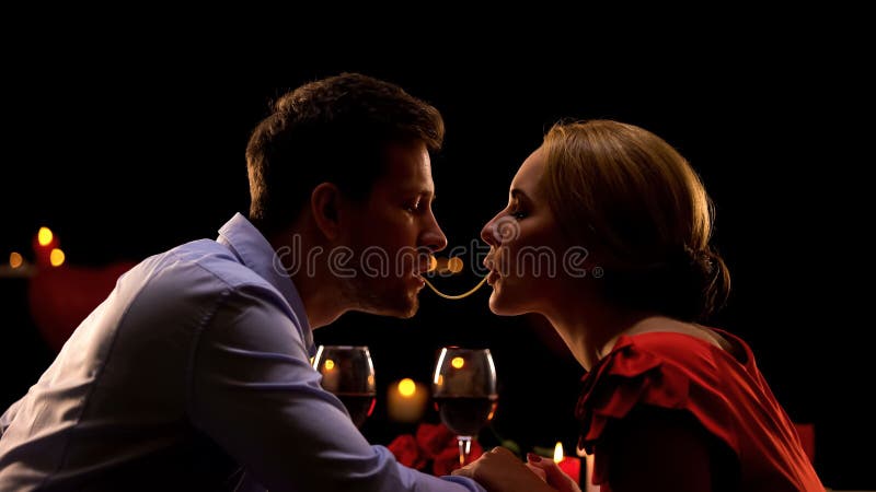 Pares bonitos que fazem os espaguetes beijar na data romântica no restaurante, amor imagem de stock Pares bonitos que fazem os espaguetes beijar na data romântica no restaurante, amor imagem de stock