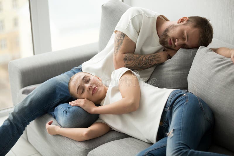 Pares cansados relajados que duermen teniendo siesta en el tog cómodo del sofá fotografía de archivo libre de regalías Pares cansados relajados que duermen teniendo siesta en el tog cómodo del sofá fotografía de archivo libre de regalías