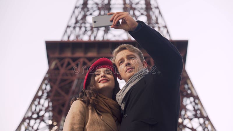 Pares cariñosos felices de los turistas que hacen el selfie en el fondo de la torre Eiffel