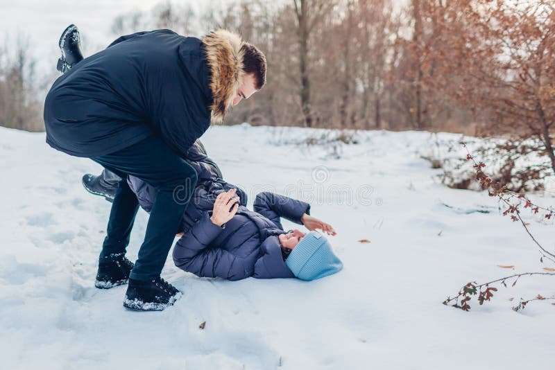 Pares cariñosos hermosos que juegan en el hombre del bosque del invierno que detiene y que empuja a la novia en nieve Gente que s foto de archivo libre de regalías Pares cariñosos hermosos que juegan en el hombre del bosque del invierno que detiene y que empuja a la novia en nieve Gente que s foto de archivo libre de regalías