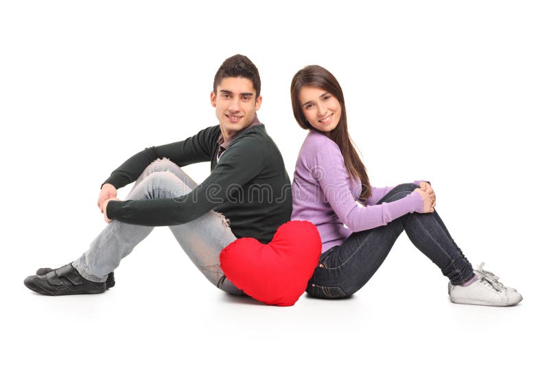 Young loving couple and a red heart shaped pillow on white background. Young loving couple and a red heart shaped pillow on white background