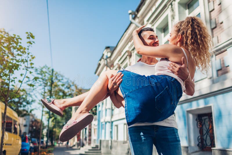Pares da raça misturada no amor que anda na cidade Homem árabe que guarda sua amiga nas mãos Aperto dos jovens imagem de stock Pares da raça misturada no amor que anda na cidade Homem árabe que guarda sua amiga nas mãos Aperto dos jovens imagem de stock