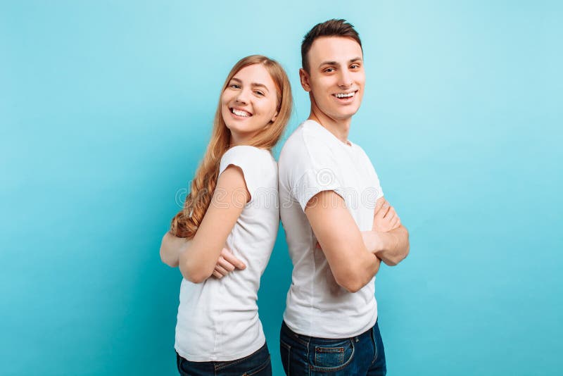 Pares de amor, homem e mulher, vestidos nos t-shirt brancos, lado a lado e sorrindo, contra um fundo azul imagem de stock royalty free Pares de amor, homem e mulher, vestidos nos t-shirt brancos, lado a lado e sorrindo, contra um fundo azul imagem de stock royalty free