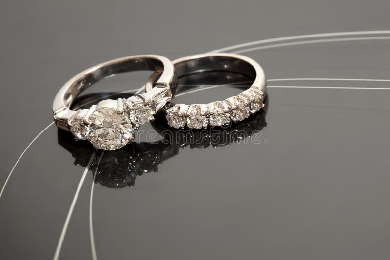 A pair of wedding rings on a reflective grey surface. A pair of wedding rings on a reflective grey surface.