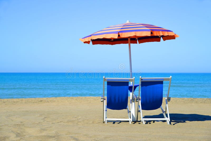 Pair of sun loungers and sunshade umbrella on the beach. Vacation concept. Pair of sun loungers and sunshade umbrella on the beach. Vacation concept.