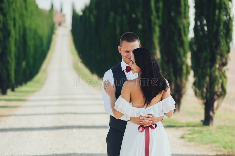 Pares de sorriso à moda felizes que andam e que beijam em Toscânia, AIE foto de stock Pares de sorriso à moda felizes que andam e que beijam em Toscânia, AIE foto de stock