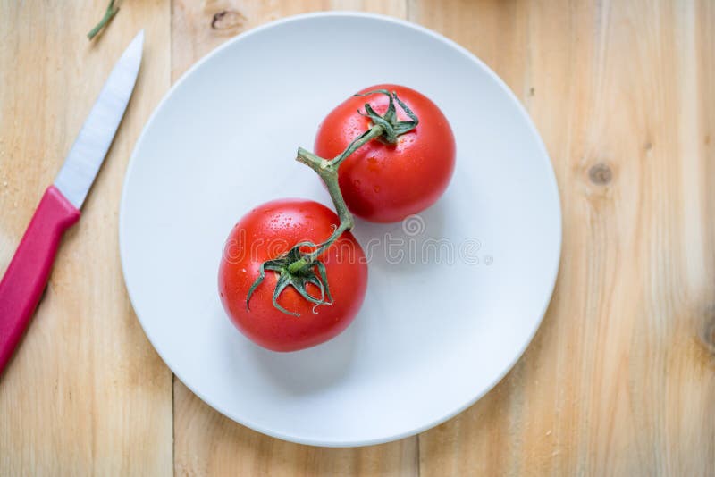 Pares de tomates vermelhos frescos em uma placa branca imagem de stock Pares de tomates vermelhos frescos em uma placa branca imagem de stock