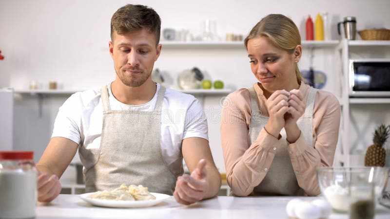 Pares divertidos que miran la pasta cruda, malas cocinas, cocinando los cursos para los aficionados imágenes de archivo libres de regalías Pares divertidos que miran la pasta cruda, malas cocinas, cocinando los cursos para los aficionados imágenes de archivo libres de regalías