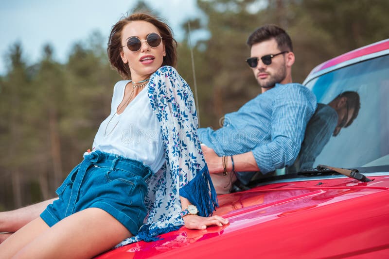 pares elegantes jovenes en las gafas de sol que se sientan en rojo fotos de archivo libres de regalías pares elegantes jovenes en las gafas de sol que se sientan en rojo fotos de archivo libres de regalías