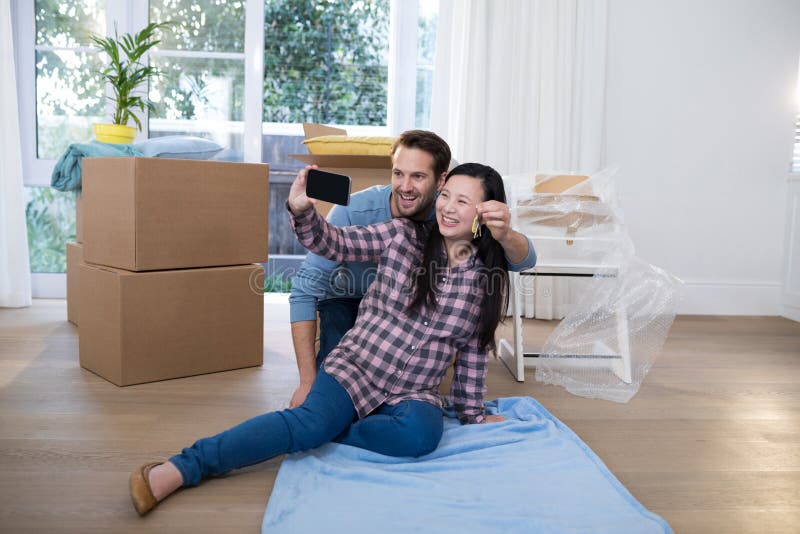 Pares embarazadas que se sostienen dominantes y que toman el selfie en nueva casa foto de archivo libre de regalías