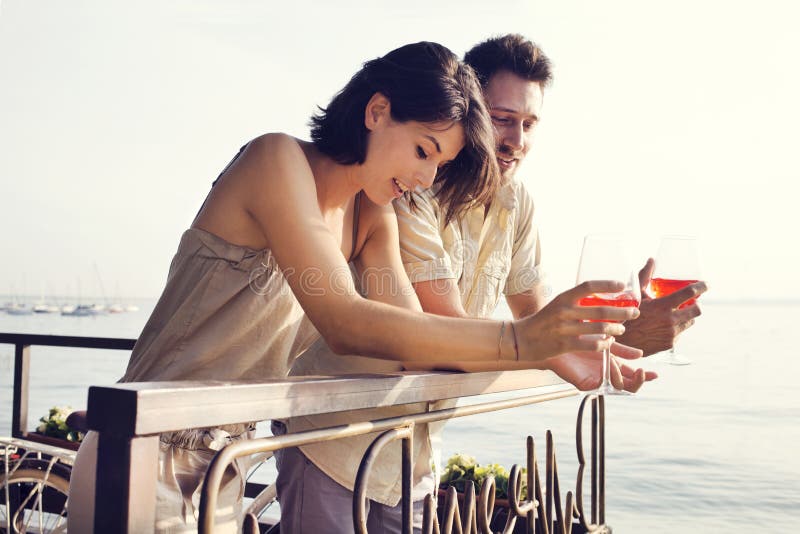 Pares en el amor que habla mientras que teniendo spritz en una terraza de la opinión del lago fotografía de archivo libre de regalías Pares en el amor que habla mientras que teniendo spritz en una terraza de la opinión del lago fotografía de archivo libre de regalías