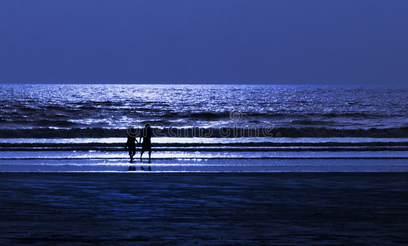 Pares en la playa el noche de la luz de luna foto de archivo Pares en la playa el noche de la luz de luna foto de archivo