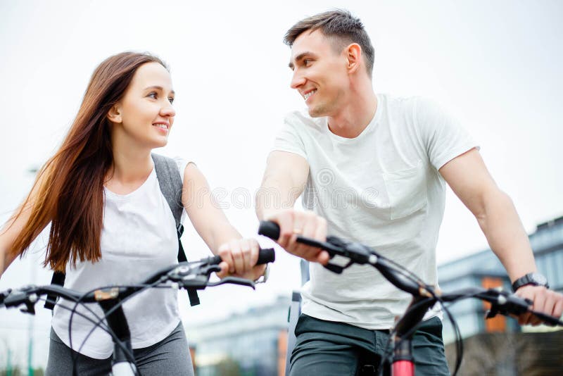 Pares en las bicis al aire libre que sonríen imagen de archivo libre de regalías Pares en las bicis al aire libre que sonríen imagen de archivo libre de regalías