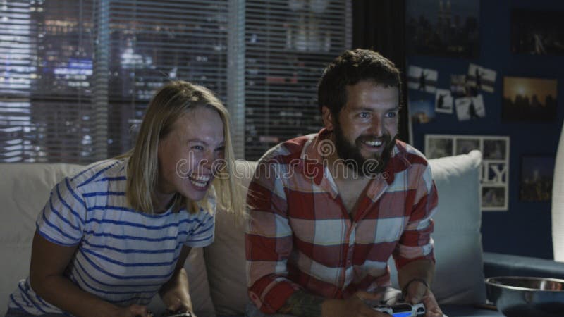 Pares expressivos que jogam o videogame em casa imagem de stock royalty free Pares expressivos que jogam o videogame em casa imagem de stock royalty free
