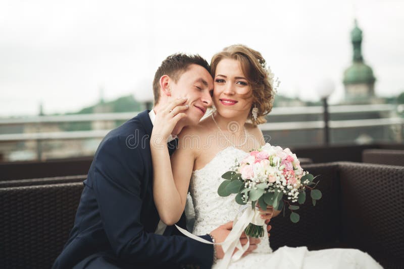 Pares felices de la boda, novia, novio que se besa con vista de la ciudad vieja imagen de archivo libre de regalías Pares felices de la boda, novia, novio que se besa con vista de la ciudad vieja imagen de archivo libre de regalías