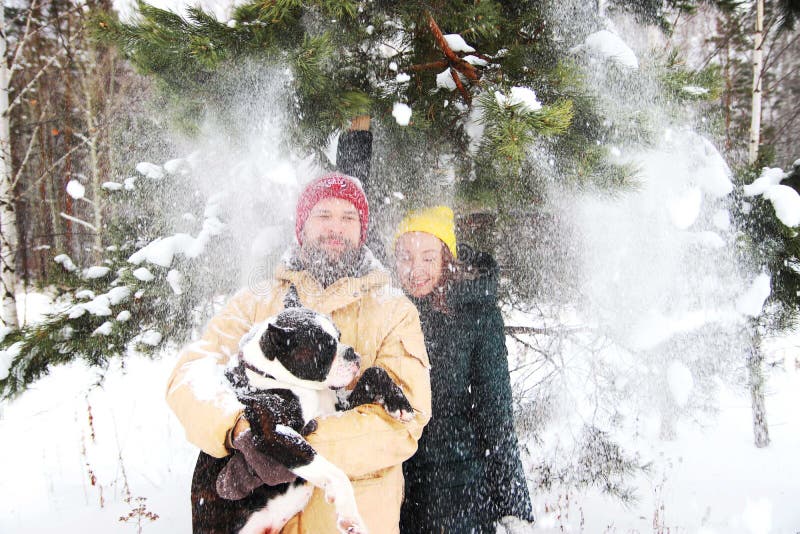 Pares felices en el amor que se divierte en la nieve con su perro del bebé fotografía de archivo Pares felices en el amor que se divierte en la nieve con su perro del bebé fotografía de archivo