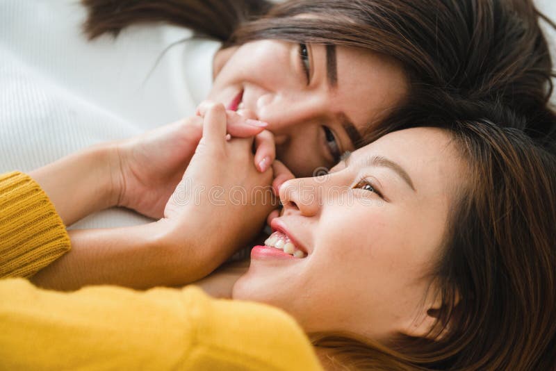 Pares felices lesbianos asiáticos jovenes hermosos de las mujeres LGBT que abrazan y que sonríen mientras que miente junto en cam imagenes de archivo Pares felices lesbianos asiáticos jovenes hermosos de las mujeres LGBT que abrazan y que sonríen mientras que miente junto en cam imagenes de archivo