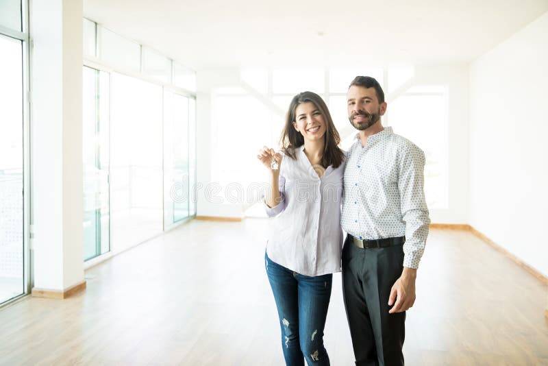 Pares felices que llevan a cabo llaves en su nuevo hogar foto de archivo libre de regalías Pares felices que llevan a cabo llaves en su nuevo hogar foto de archivo libre de regalías