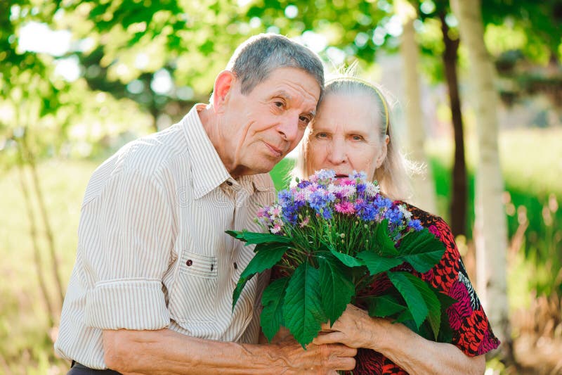 Pares felizes e muito velhos que sorriem em um parque em um dia ensolarado imagem de stock Pares felizes e muito velhos que sorriem em um parque em um dia ensolarado imagem de stock