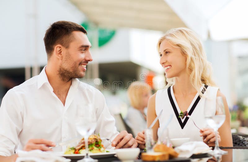 Pares felizes que comem o jantar no terraço do restaurante imagem de stock Pares felizes que comem o jantar no terraço do restaurante imagem de stock