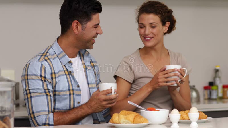 Pares felizes que conversam e que comem o café da manhã junto