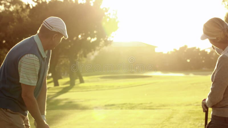 Pares felizes que teeing fora no campo de golfe