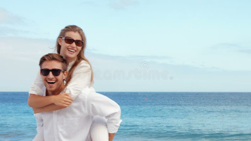 Pares felizes que têm o divertimento na praia