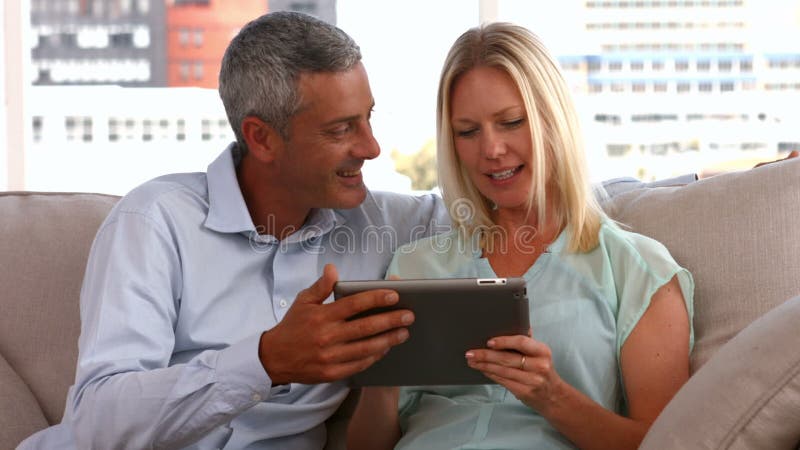 Pares felizes usando o PC da tabuleta junto vídeos de arquivo