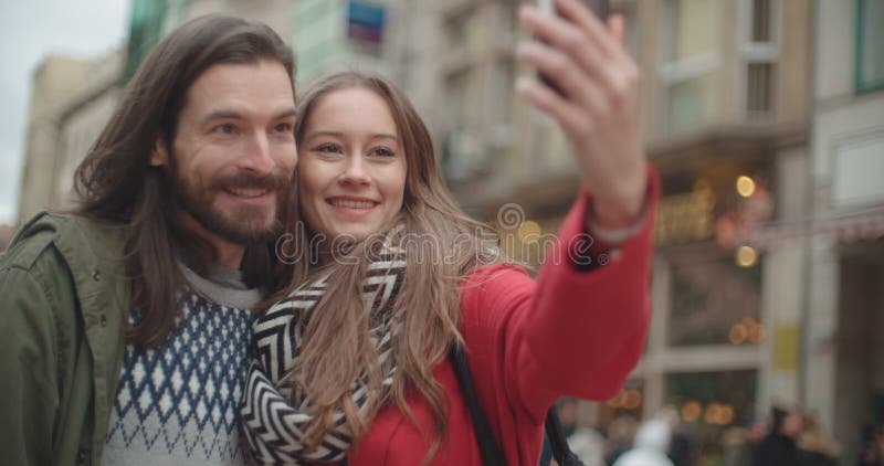 Pares hermosos jovenes que toman el selfie en una ciudad