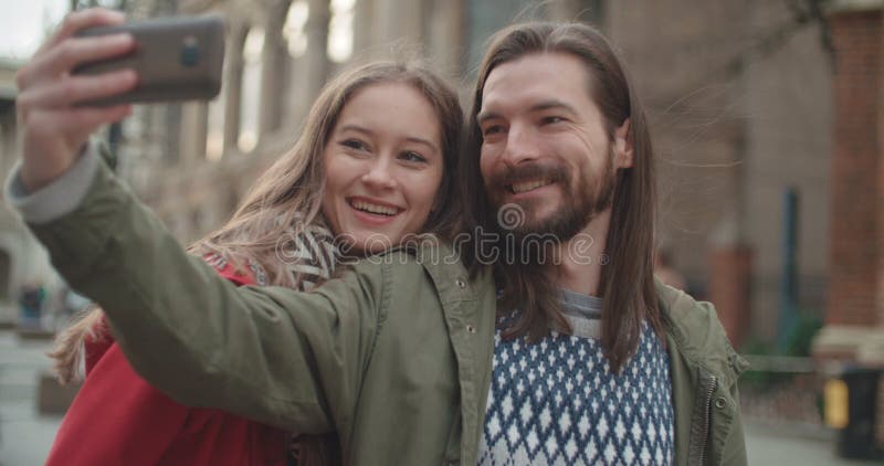 Pares hermosos jovenes que toman el selfie en una ciudad