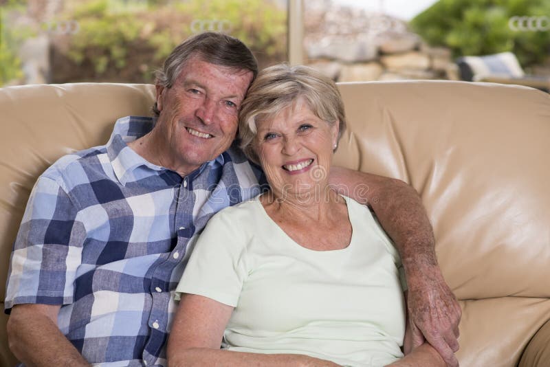 Pares hermosos mayores de la Edad Media alrededor 70 años junto en casa de la sala de estar del sofá feliz sonriente del sofá que imagenes de archivo Pares hermosos mayores de la Edad Media alrededor 70 años junto en casa de la sala de estar del sofá feliz sonriente del sofá que imagenes de archivo