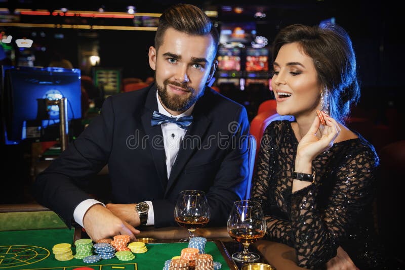 Pares hermosos y ricos que juegan la ruleta en el casino imagenes de archivo Pares hermosos y ricos que juegan la ruleta en el casino imagenes de archivo