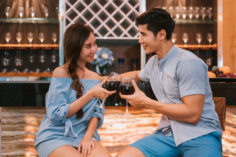 Pares jovenes asiáticos que tintinean las copas de vino en la barra nacional del lux imagen de archivo libre de regalías Pares jovenes asiáticos que tintinean las copas de vino en la barra nacional del lux imagen de archivo libre de regalías
