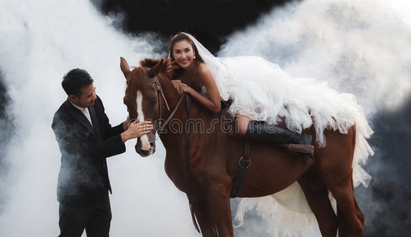 Pares jovenes del recién casado, novia hermosa de la belleza en el montar a caballo nupcial blanco del traje de la boda de la mod fotografía de archivo Pares jovenes del recién casado, novia hermosa de la belleza en el montar a caballo nupcial blanco del traje de la boda de la mod fotografía de archivo