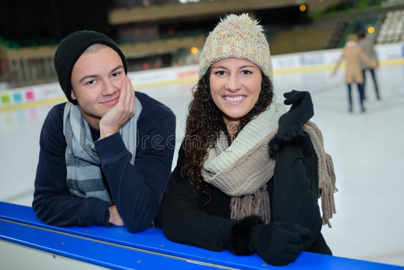 Pares jovenes del retrato en la pista de hielo lateral fotografía de archivo libre de regalías Pares jovenes del retrato en la pista de hielo lateral fotografía de archivo libre de regalías