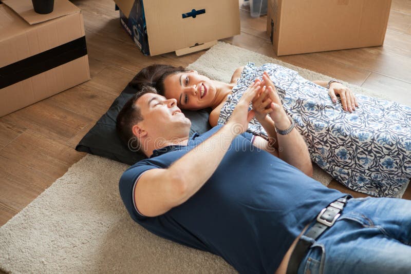 Pares jovenes en el amor que se mueve en su nuevo apartamento fotografía de archivo libre de regalías Pares jovenes en el amor que se mueve en su nuevo apartamento fotografía de archivo libre de regalías