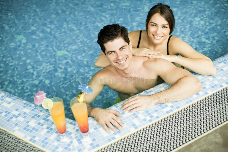 Pares jovenes en la piscina foto de archivo Pares jovenes en la piscina foto de archivo