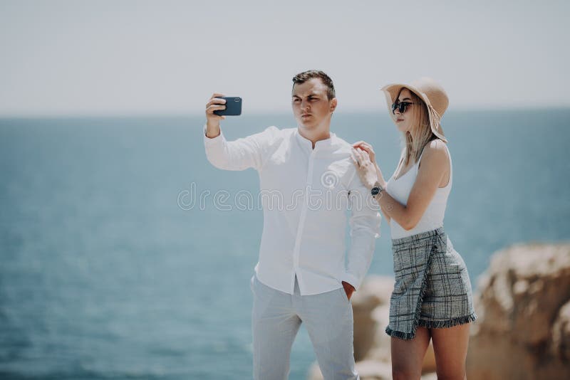 Pares jovenes felices en el amor que toma el selfie con el teléfono móvil en la playa imagen de archivo libre de regalías Pares jovenes felices en el amor que toma el selfie con el teléfono móvil en la playa imagen de archivo libre de regalías