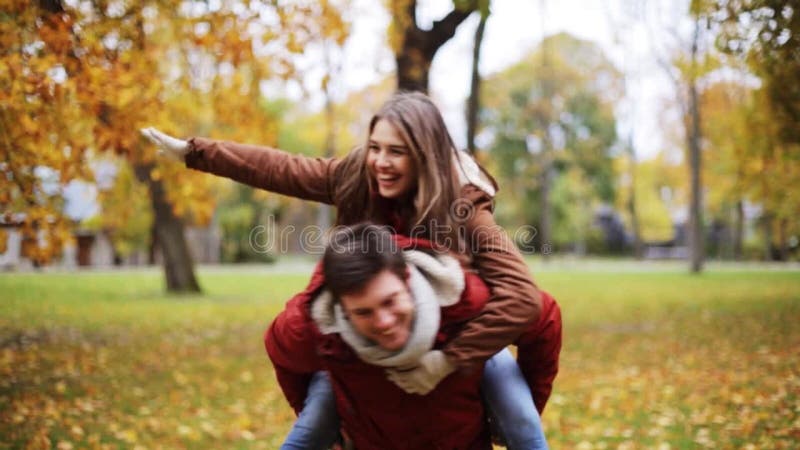 Pares jovenes felices que se divierten en parque del otoño almacen de video